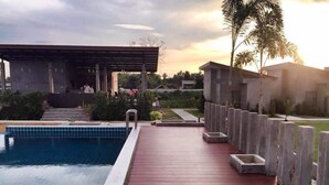 A swimming pool with a wooden deck, surrounded by a low fence and palm trees. - Baanwaan Resort Hat Yai (Hat Yai)