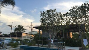 Area piscina con pergola, alberi e vista su edifici sullo sfondo.