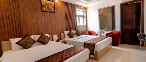A hotel room with two beds, wooden paneling on the walls, a large mirror, and a red chair.