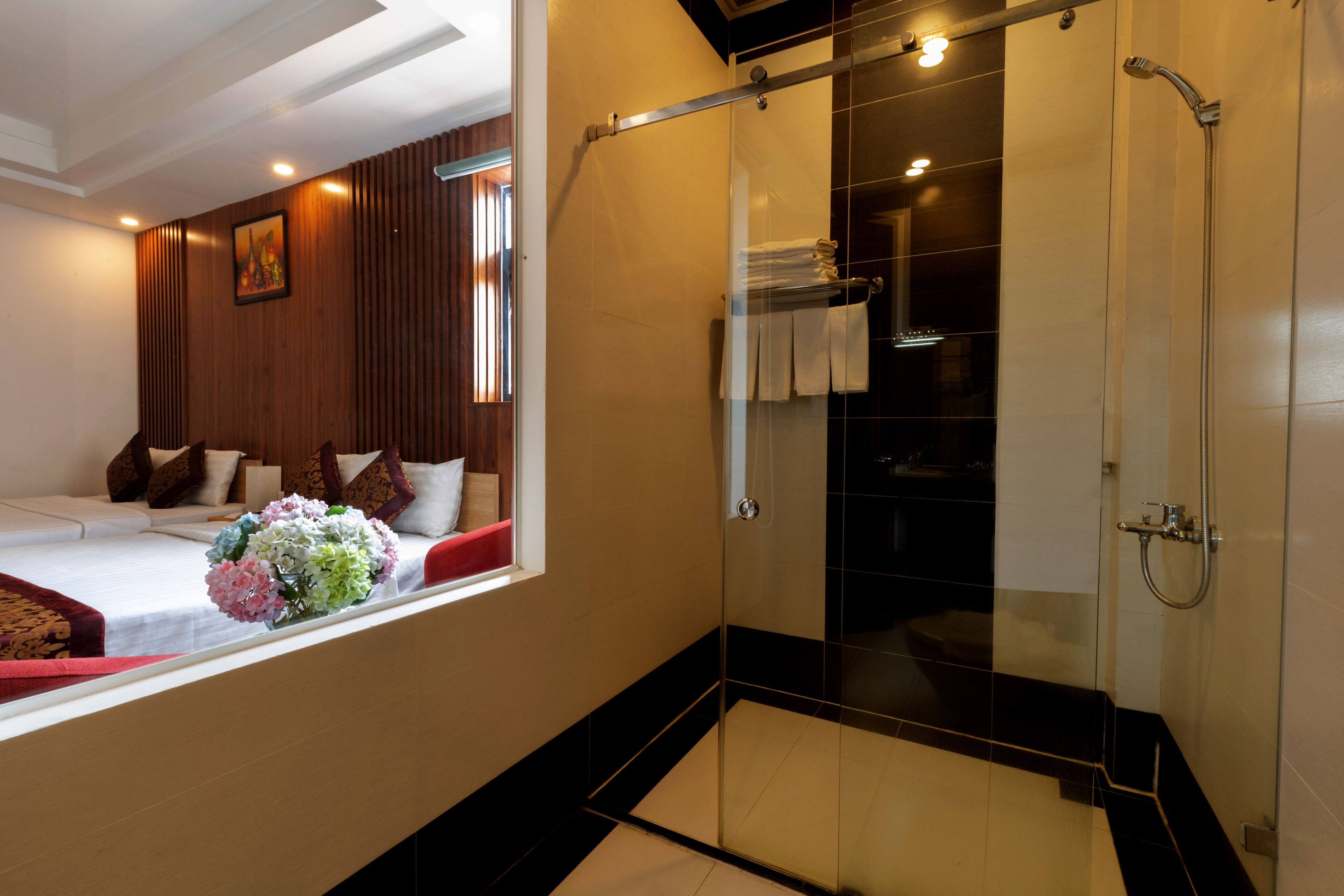 A hotel room with a bed, a window with a view, a shower area, and a wall-mounted towel rack.
