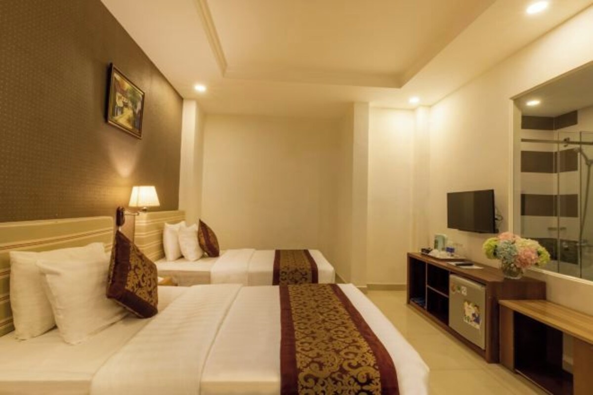 A hotel room with two beds, a TV, a desk, and a shower area.