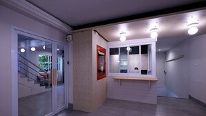 A modern hallway with a glass door leading to a staircase, a small window with a mirror, and a light fixture on the ceiling. - Siam Mansion Hat Yai (Hat Yai)