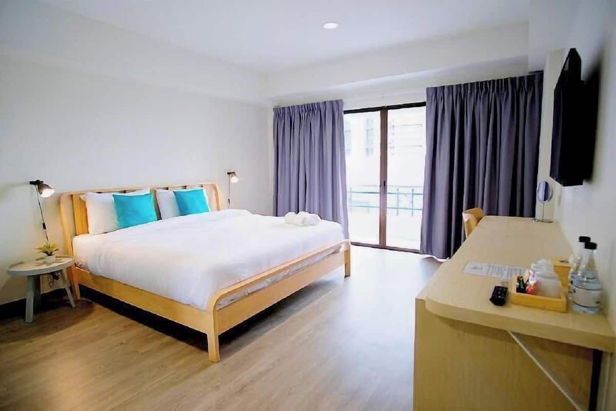 Ein Hotelzimmer mit Bett, Nachttisch, Lampe und Schreibtisch mit Stuhl.