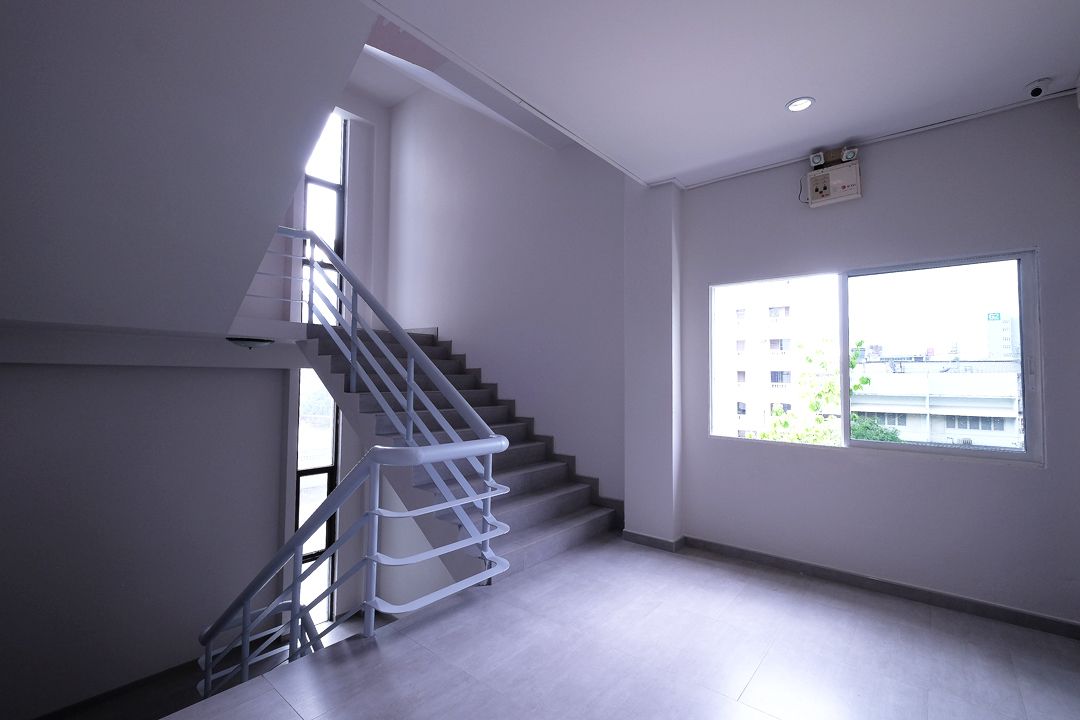 Interior moderno com escada, janelas amplas e uma tomada visível na parede.