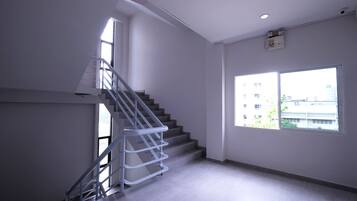 Interior moderno com escada, janelas amplas e uma tomada visível na parede.