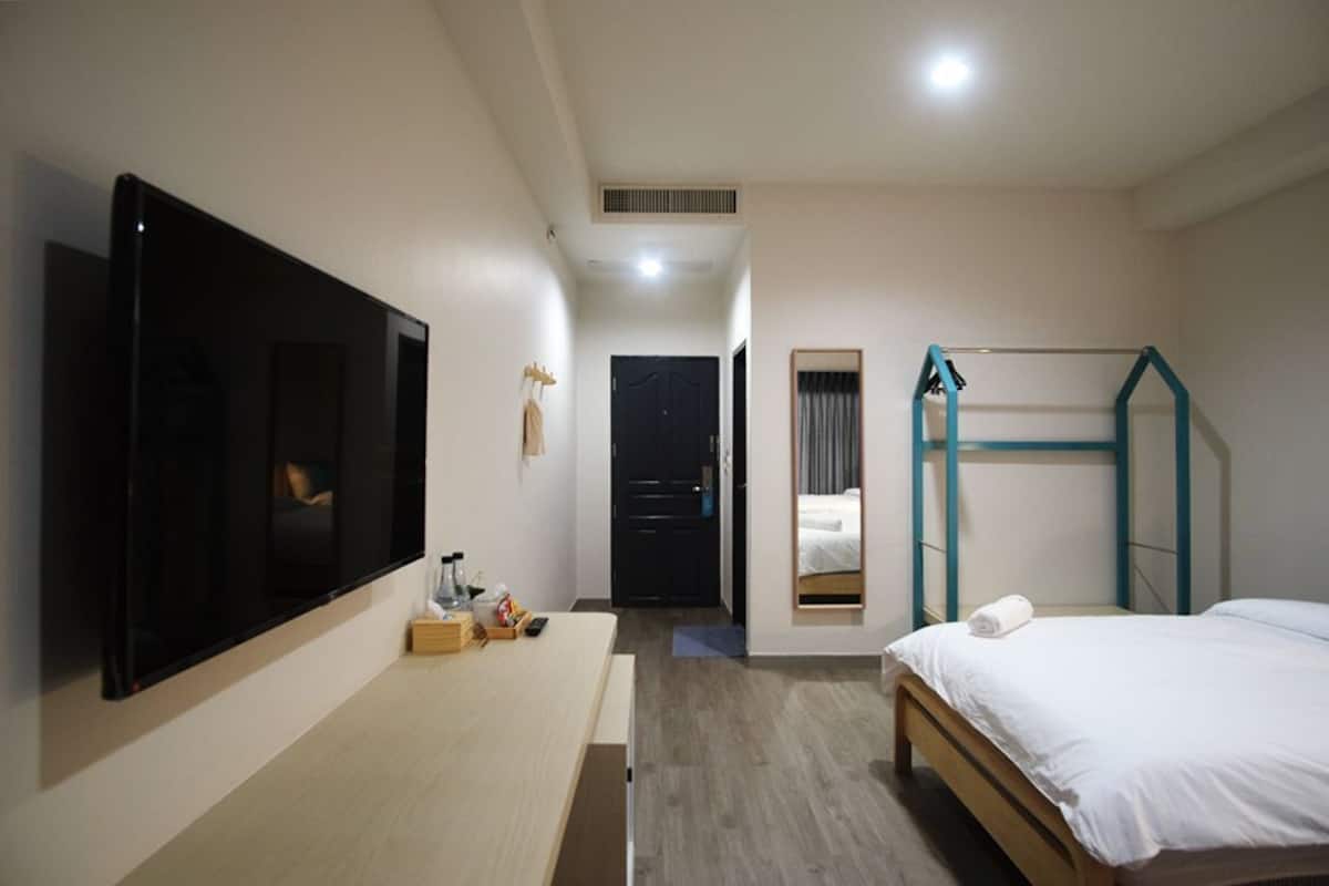 Ein Hotelzimmer mit Bett, Wandfernseher, Schreibtisch mit Stuhl und einer Etagenpritsche.