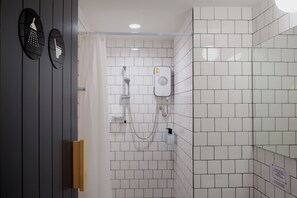 Ein Badezimmer mit weißen Fliesen, einer Dusche und einem WC.