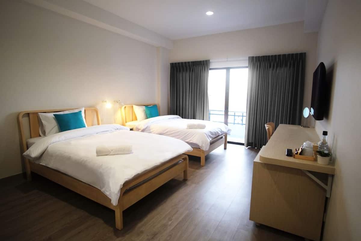 Ein Hotelzimmer mit zwei Einzelbetten, einem Schreibtisch und einem großen Fenster mit Vorhängen.