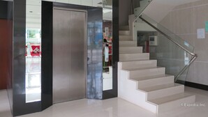 Un intérieur moderne avec un escalier, une rambarde en verre et un ascenseur métallique.