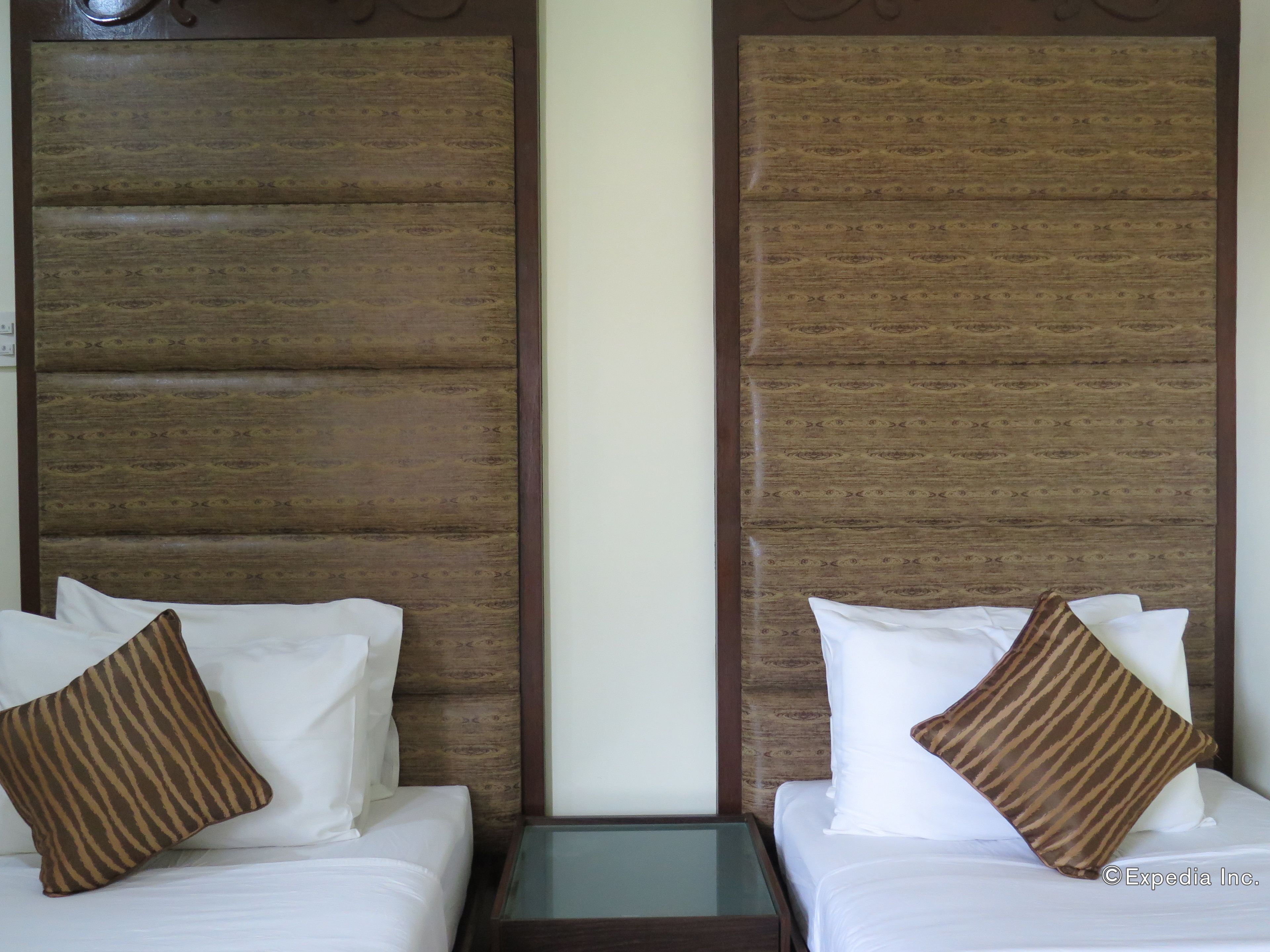 A hotel room with two beds, each with white linens and striped pillows.