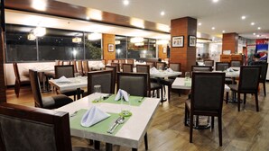 Un restaurant doté de nombreuses tables et chaises, de grandes fenêtres et d’un aménagement intérieur moderne.