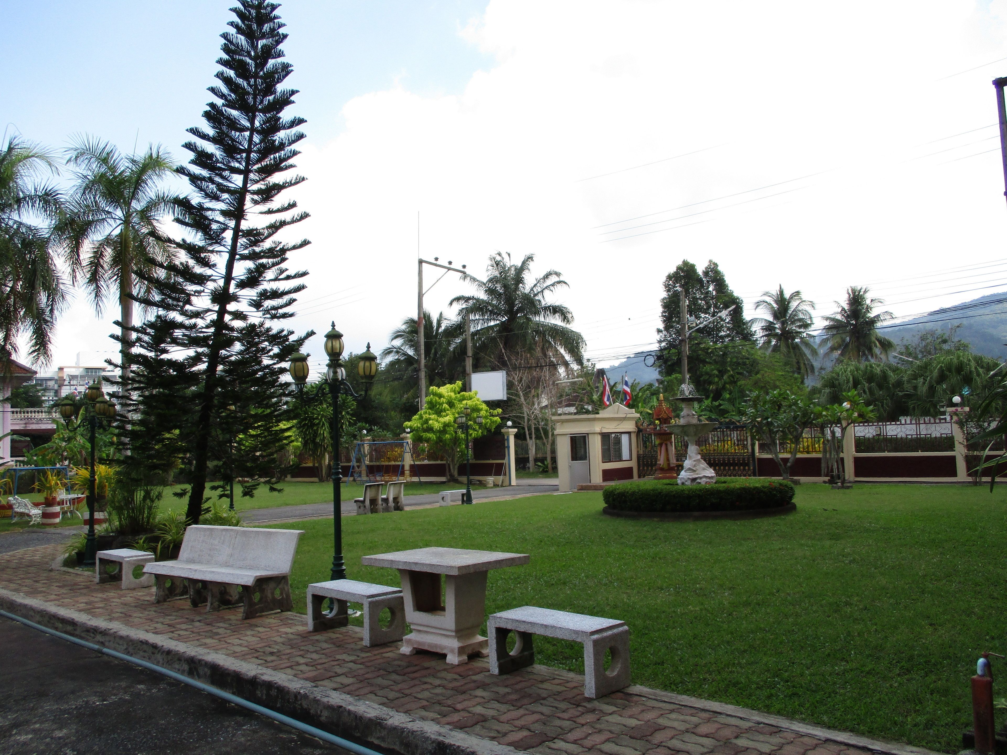 A park with benches, a fountain, and palm trees.