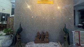 A stone wall with a golden emblem and three statues of figures. - Muang Thong Family Suite Hat Yai (Hat Yai)