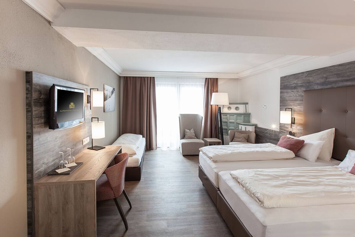 Une chambre d’hôtel équipée d’un bureau, de deux lits, d’une chaise, d’une télévision et offrant une vue sur l’extérieur.