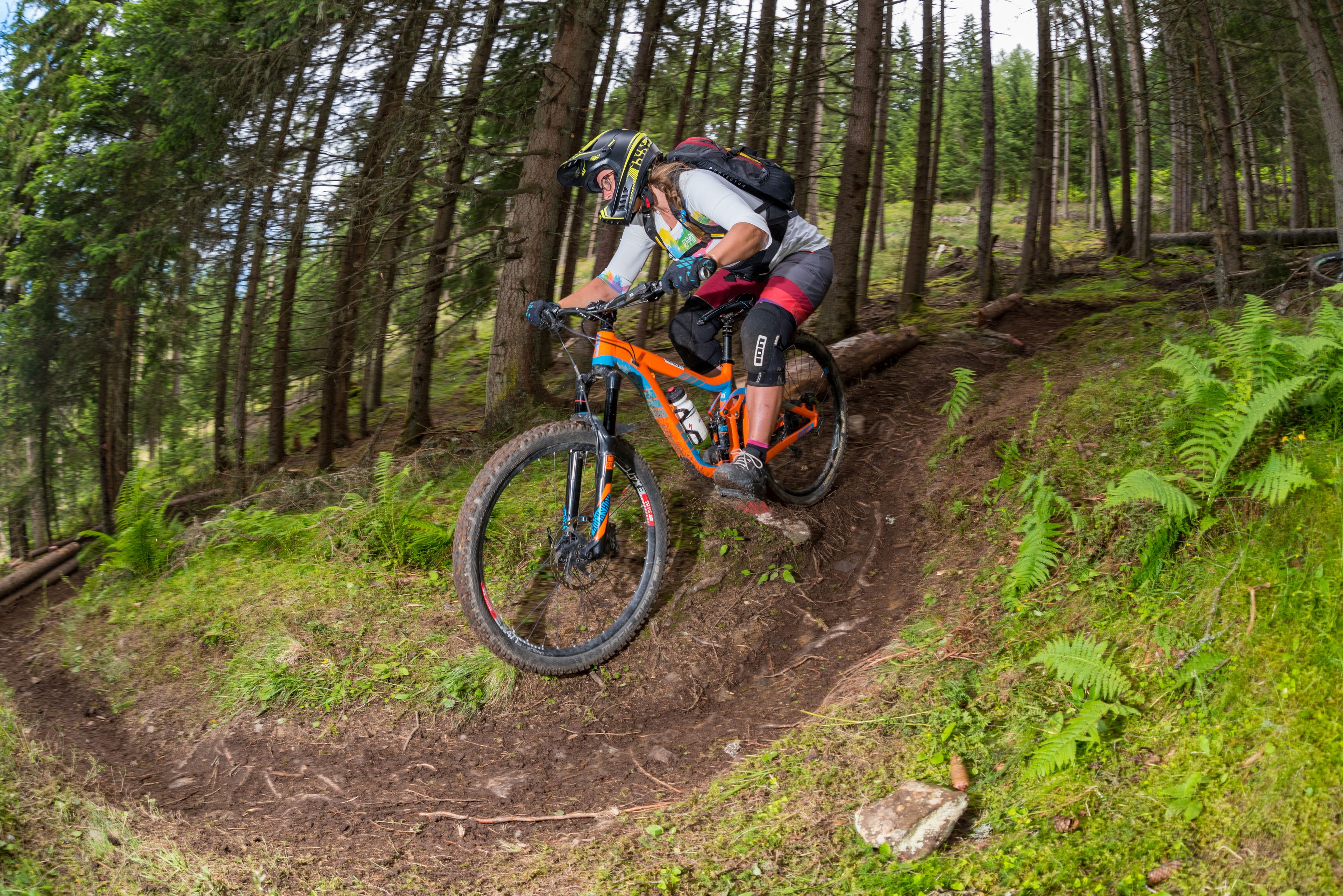 A mountain biker on a dirt trail surrounded by dense forest.