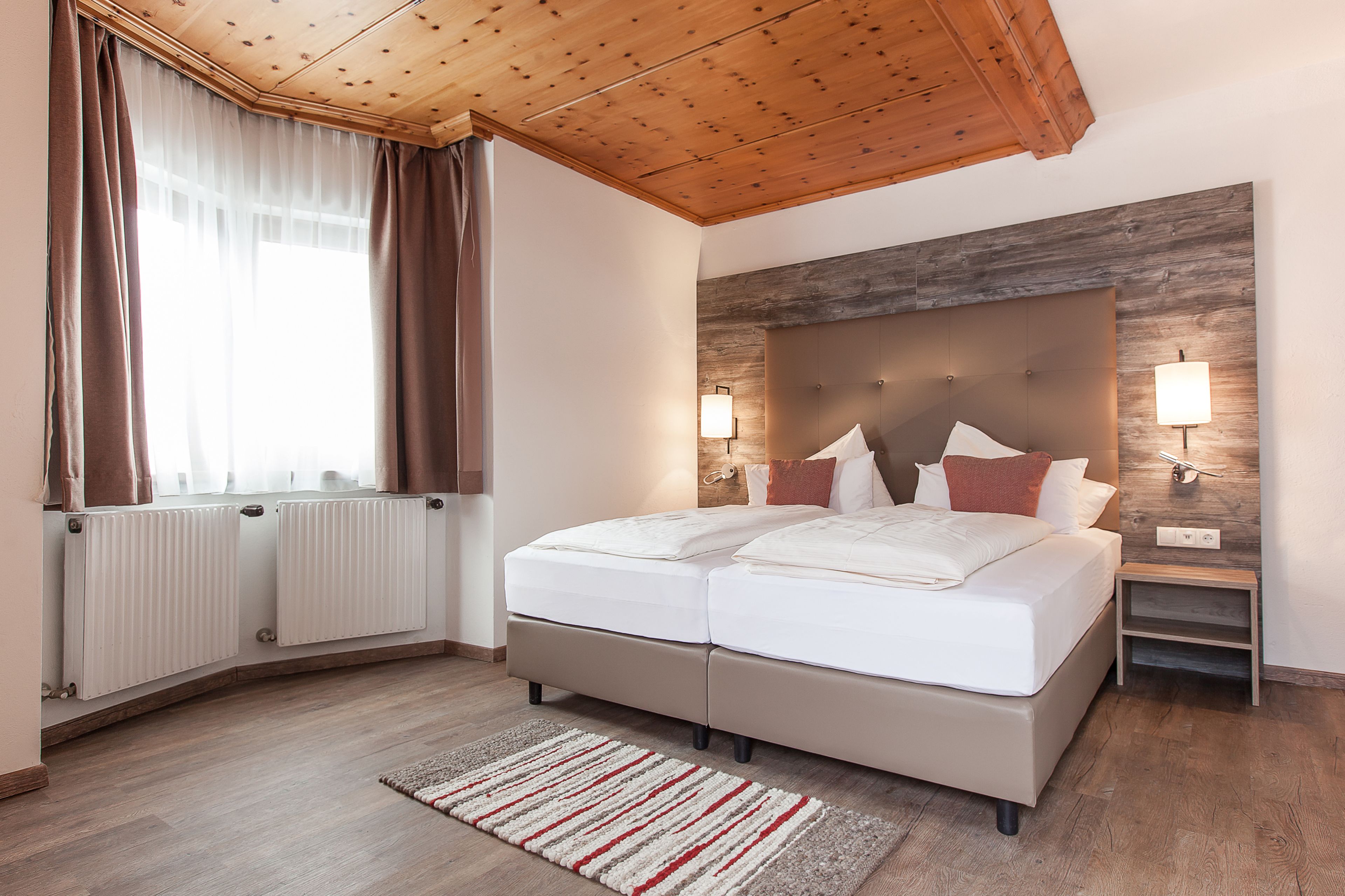 Camera da letto moderna con un letto grande, soffitto in legno e due lampade da comodino.