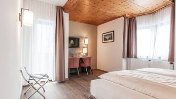 Une chambre d’hôtel avec un plafond en bois, un lit, un bureau avec des chaises et un téléviseur.