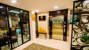 A hotel lobby with a patterned carpet, a reception desk, and a decorative wall with a television. - Klongrien Boutique (Hat Yai)