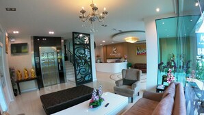 A modern hotel lobby with a reception desk, seating area, and a staircase. - Klongrien Boutique (Hat Yai)