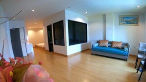 A modern living room with a sofa, a dining table, and a large window. - Klongrien Boutique (Hat Yai)