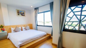 A hotel room with a bed, a nightstand, a window with curtains, and a painting on the wall. - Klongrien Boutique (Hat Yai)