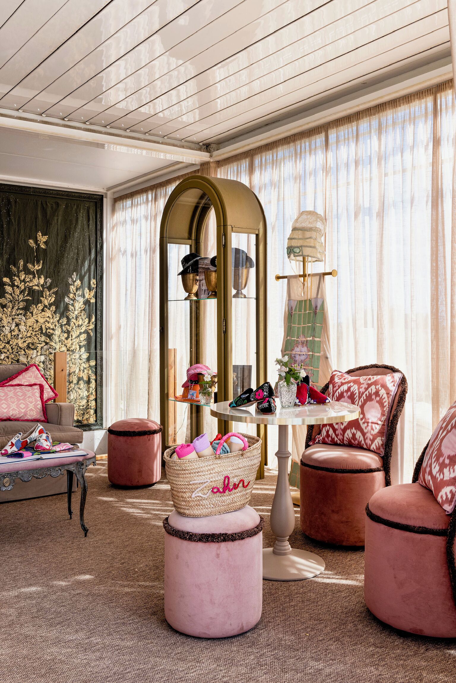 A cozy room with a sofa, ottomans, a table with shoes, and a mirror.
