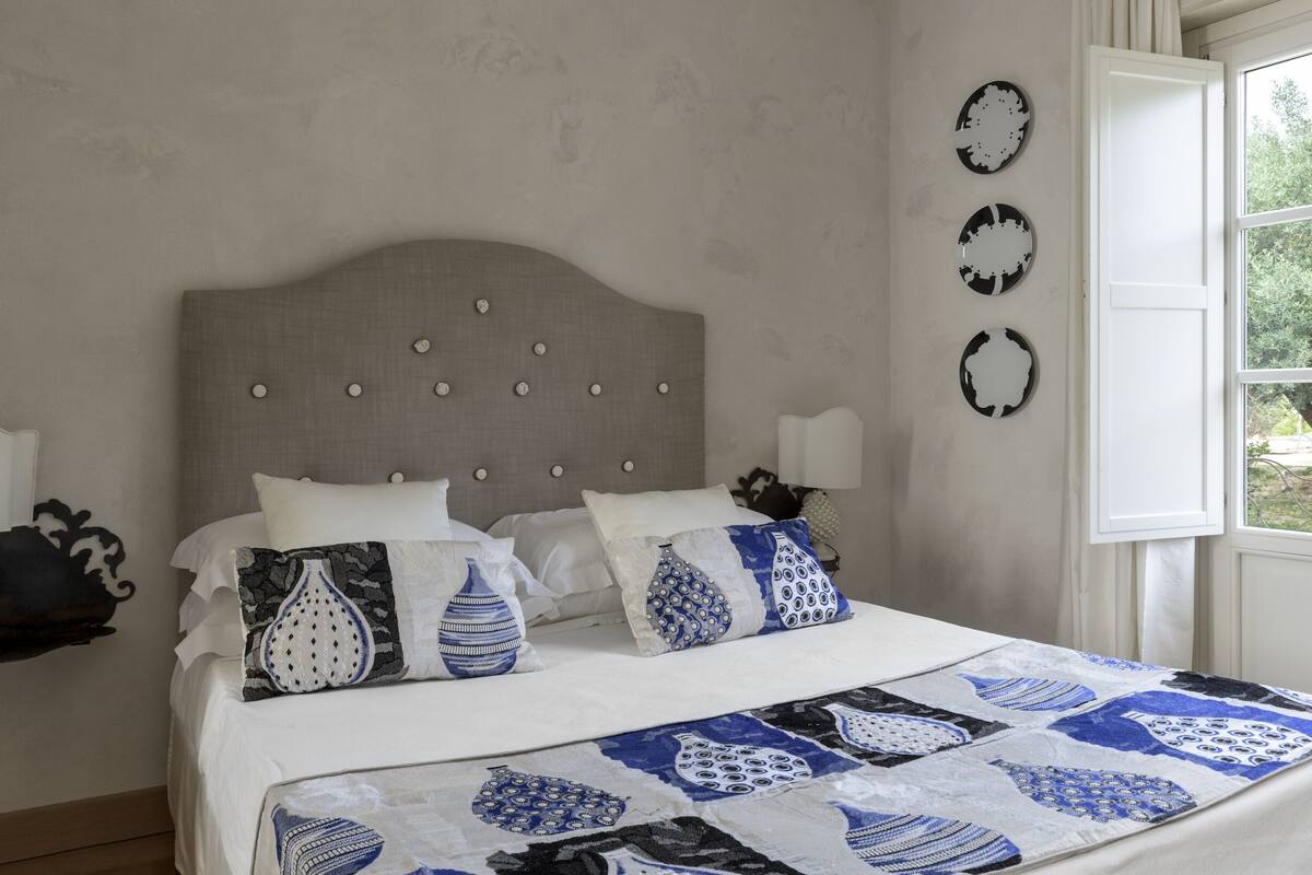 Ein Schlafzimmer mit einem Bett, Kissen, einer Kopfteil und Wanddekorationen.