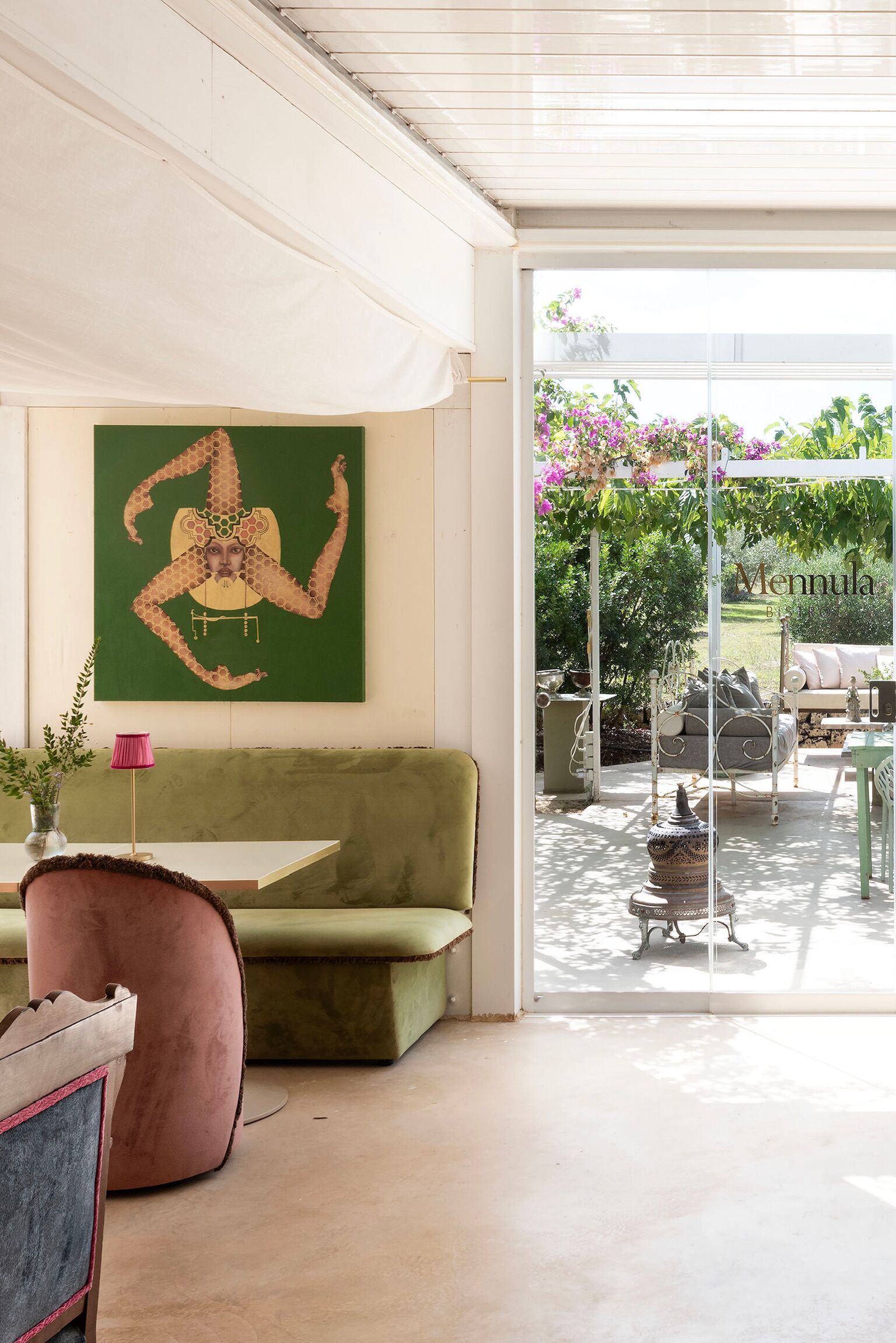 Una sala de estar moderna con un sofá verde, un sillón rosa y un cuadro abstracto grande en la pared.
