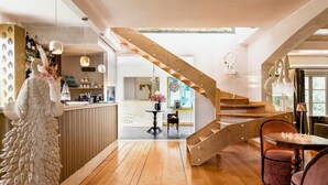 Een modern interieur met een houten trap, een receptiebalie met decoratieve objecten, en een eetgedeelte met een tafel gedekt voor twee personen.