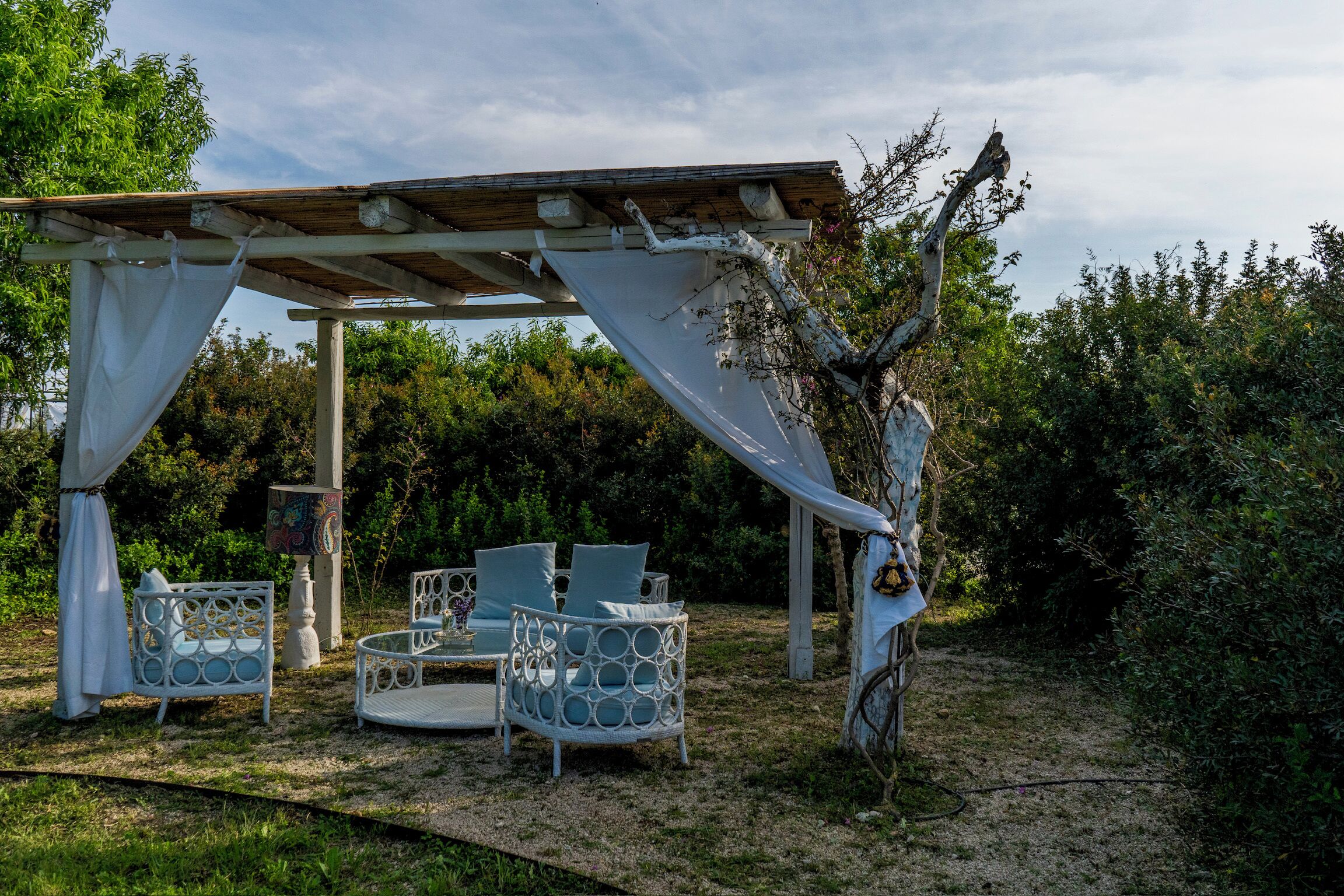 An outdoor patio with white furniture and a pergola structure.