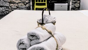 A neatly folded towel on a bed with a stone wall and framed pictures in the background. - B&B Siracusa (Syracuse)
