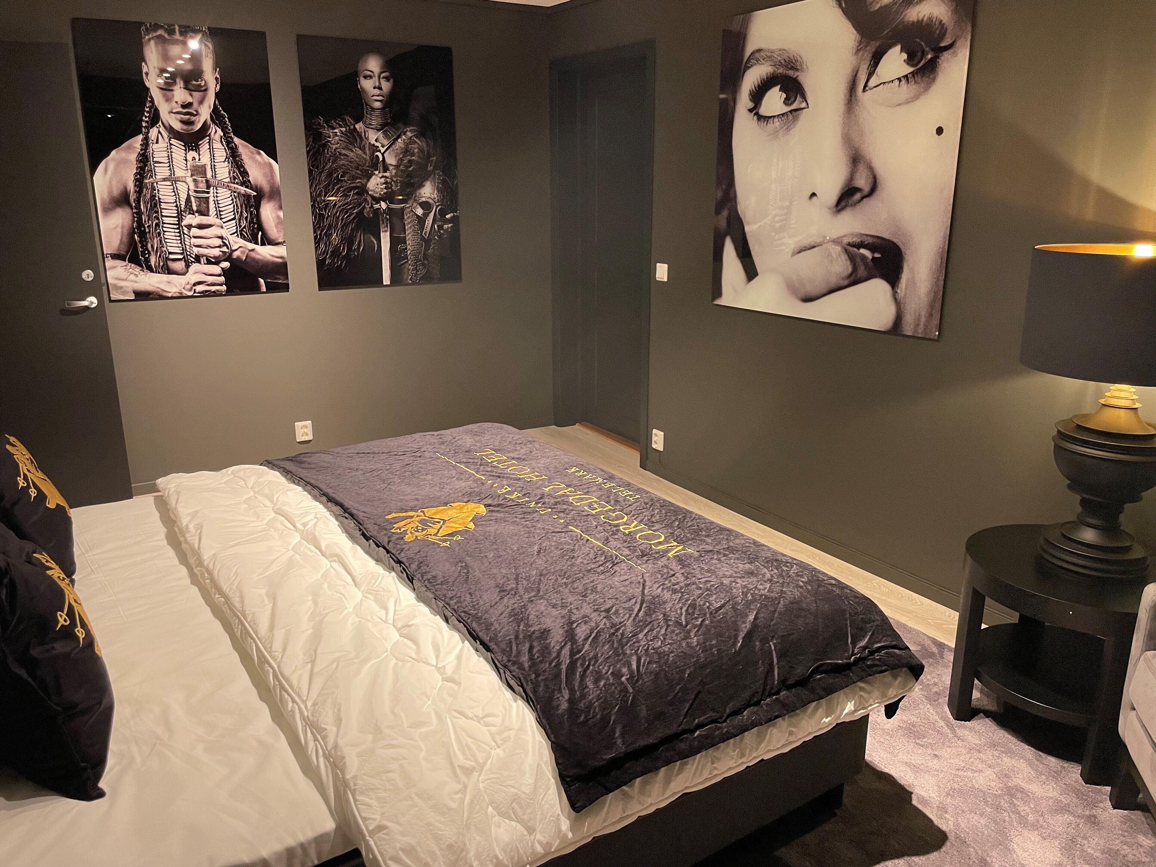 A bedroom with a bed, a nightstand, and wall art.