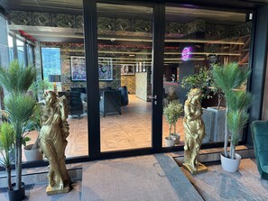 Et moderne interiør med en glasklarlåge, krukker med planter og en neonlys-skiltning.