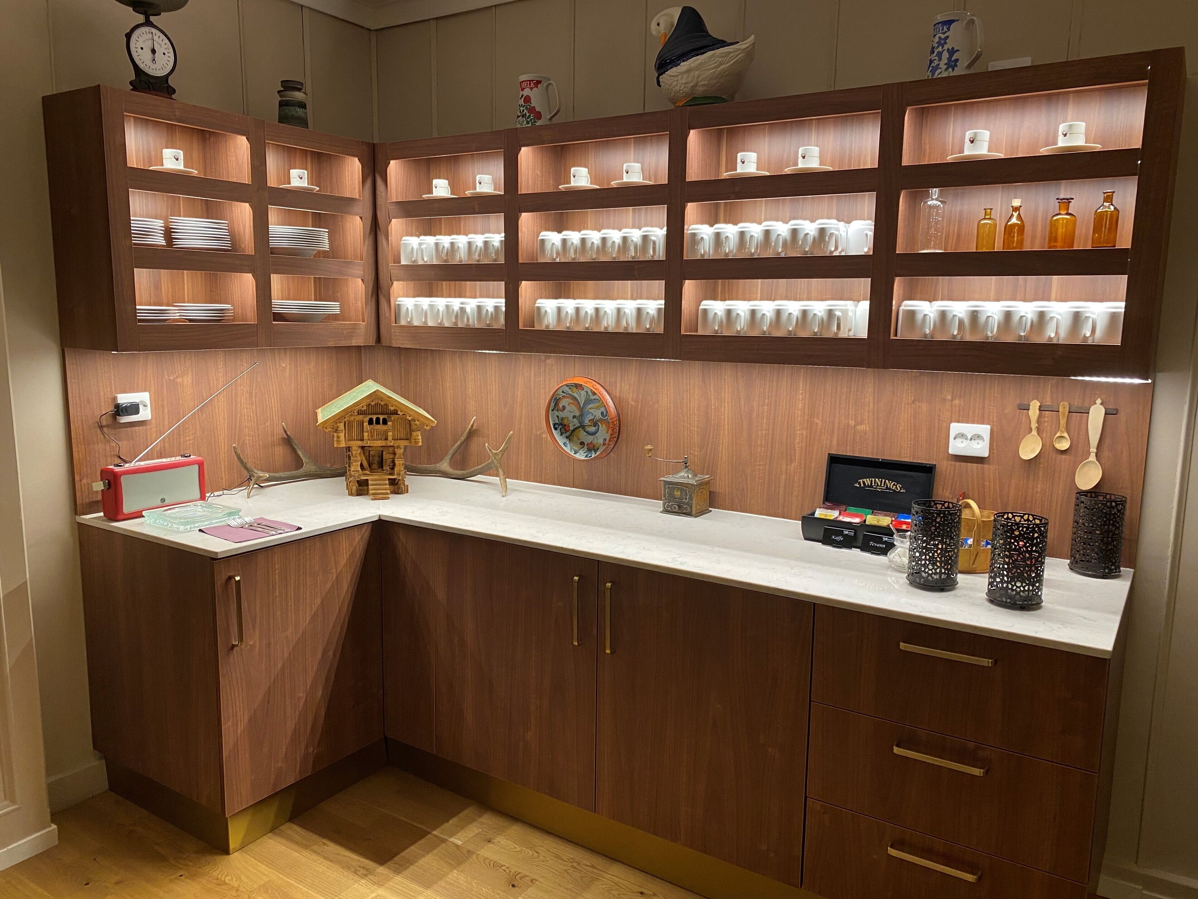 Una cucina con mobili in legno, un piano di lavoro bianco e diversi utensili da cucina.