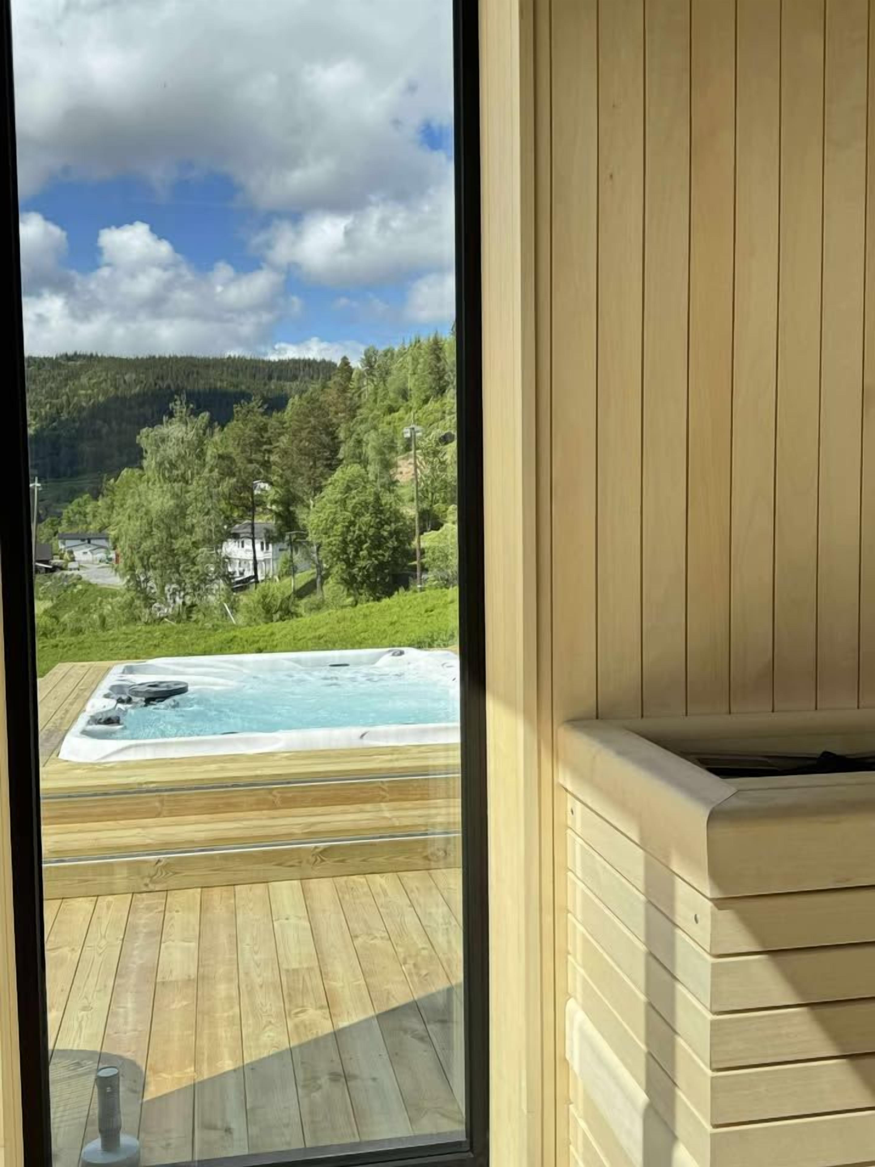 A wooden deck with a hot tub and a view of a forested hillside.