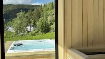 A wooden deck with a hot tub and a view of a forested hillside.