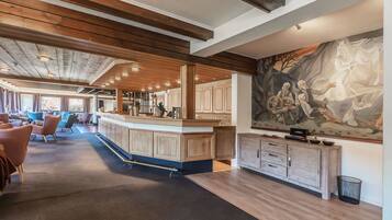 A spacious lobby with a wooden ceiling, a bar area, and a large mural on the wall.