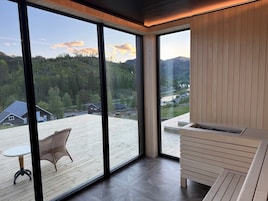 Una habitación moderna con ventanas amplias, una terraza de madera y vista a un área boscosa.