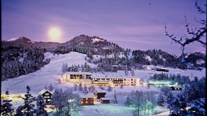 Suuri, useita kerroksia käsittävä hotelli, jossa on moderni muotoilu. Se sijaitsee lumihangen peittämällä kukkulalla, jonka ympärillä on puita.