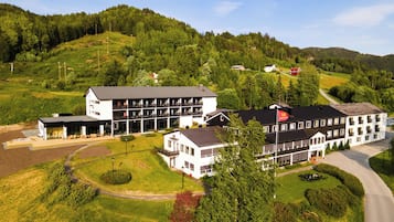 Um hotel com vários edifícios, incluindo um corpo principal com varandas e uma ala menor.