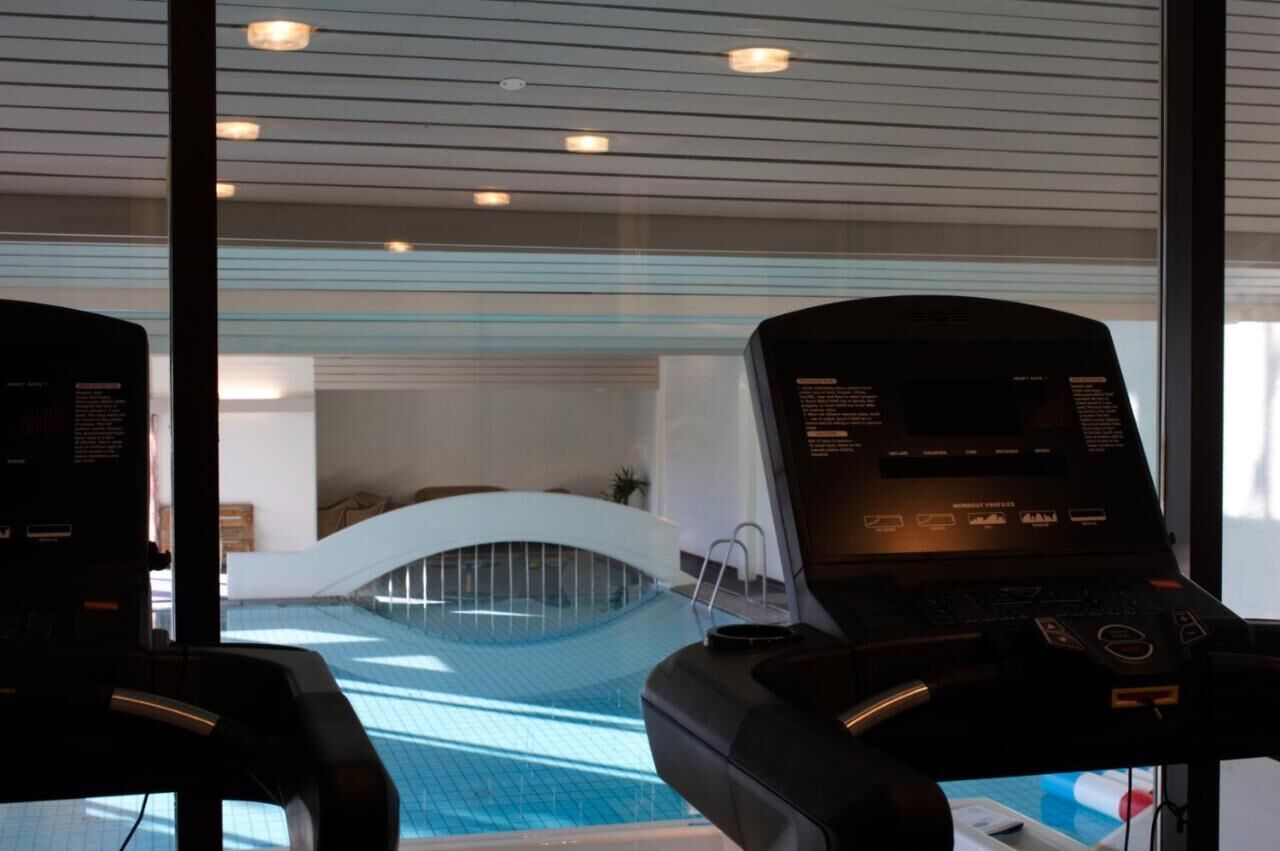 A modern indoor swimming pool with a curved ceiling and a view of a lounge area.