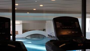 Ein moderner, überdachter Pool mit gewölbter Decke und Blick auf einen Lounge-Bereich.
