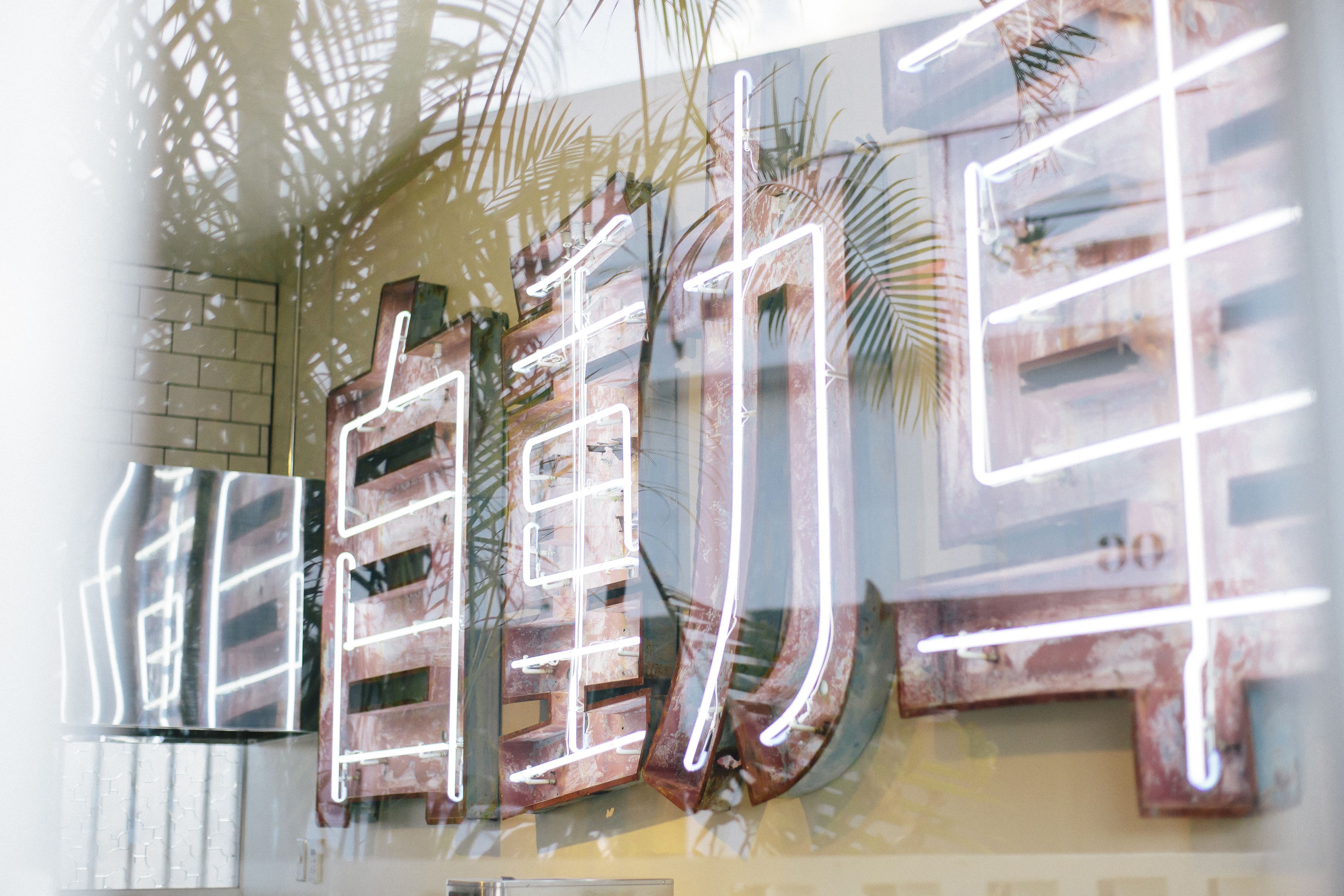 A modern interior with a glass wall, wooden panels, and a neon sign.
