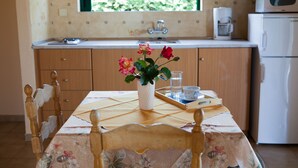 Una cocina con armarios de madera, un refrigerador blanco, una cafetera y un florero con flores sobre la mesa.