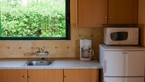 Una cocina con ventana, un lavamanos, una cafetera y un microondas.