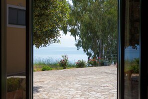 A stone-paved patio with a view of the sea and surrounding greenery. - 9 Muses Villas (Messini)