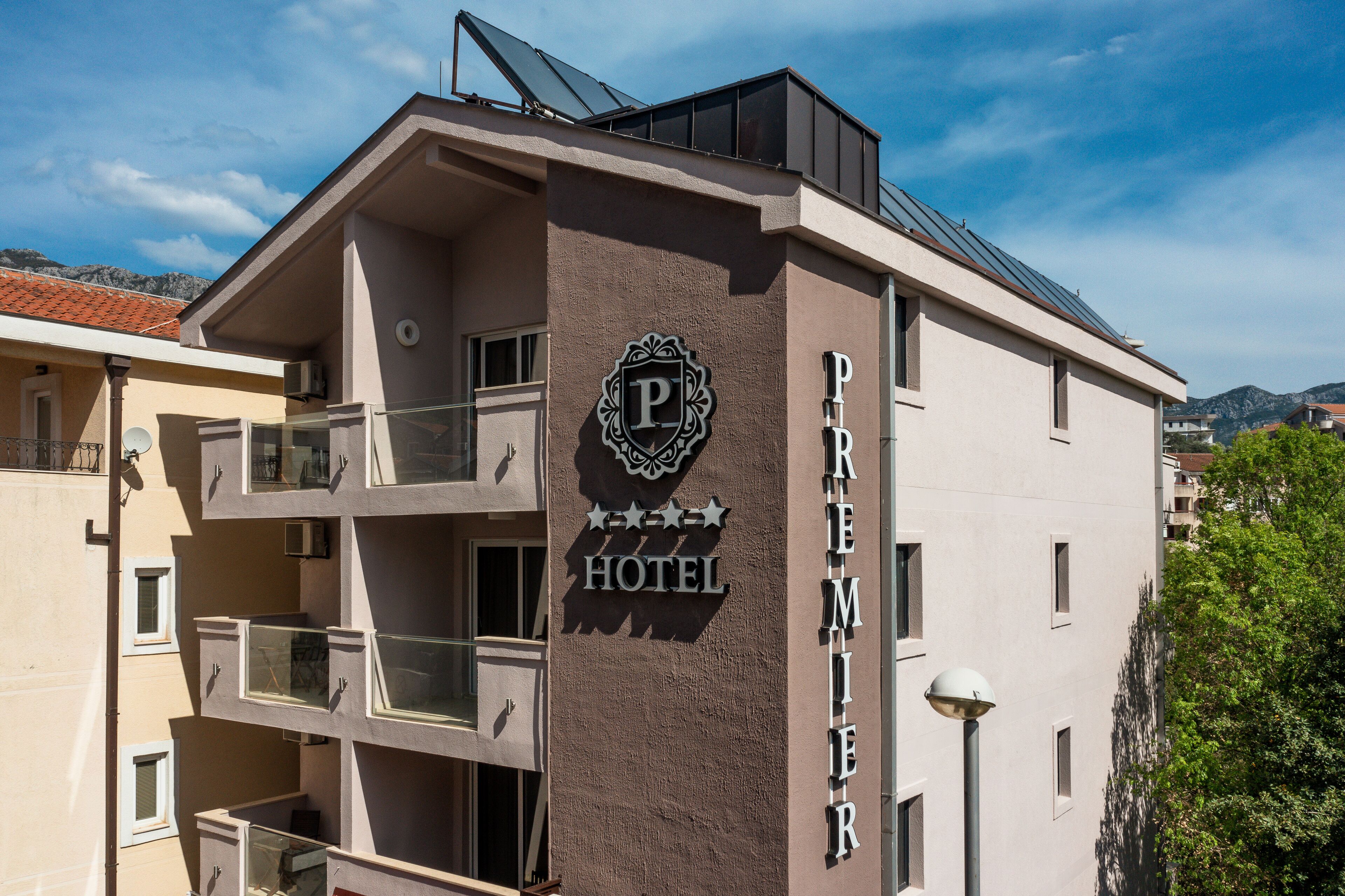 A hotel with a prominent sign reading "Premier Hotel" and a balcony with glass railings.