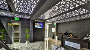 Un vestíbulo moderno con una recepción, una pantalla de televisión y una escalera.