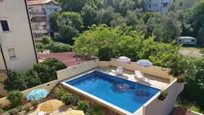 Una piscina en la azotea con vistas a edificios y árboles circundantes.