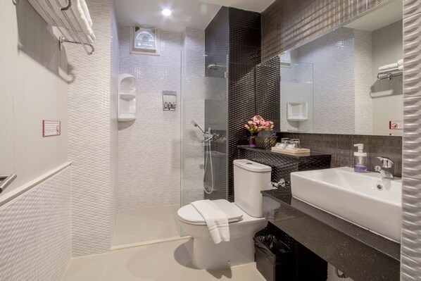A modern bathroom with a glass-enclosed shower, a white toilet, and a sink with a mirror above it.